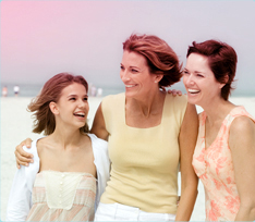 Bild på 3 kvinnor som håller om varandra, en yngre kvinna till vänster och två äldre kvinnor till höger. 