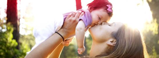 Bild på en kvinna som pussar och håller en bebis.