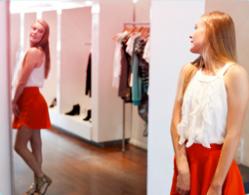Bild på en flicka som står framför en spegel och provar kläder.