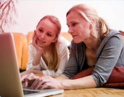 Bild på mor och dotter som använder en dator tillsammans. Bilden illustrerar vikten av kommunikation och att hjälpa din dotter att hitta rätt information.