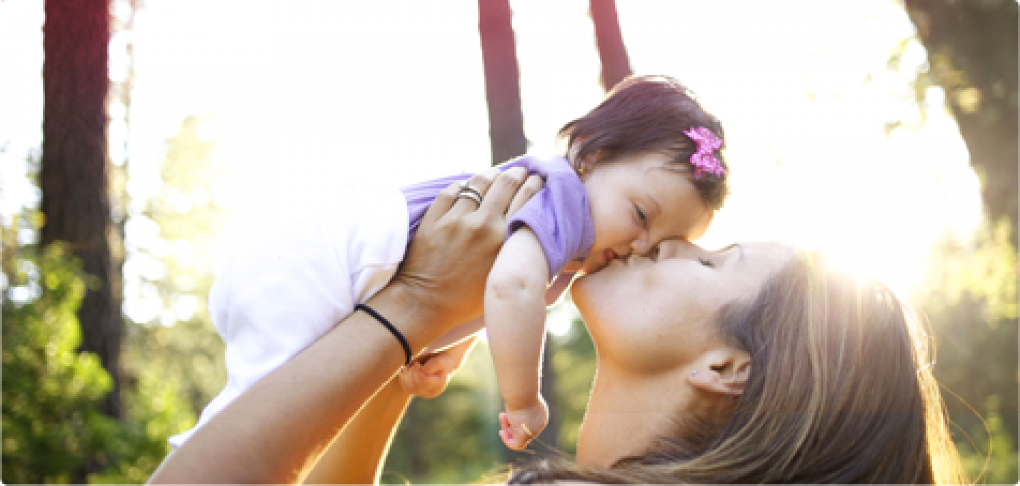 Bild på en kvinna som pussar och håller en bebis. 